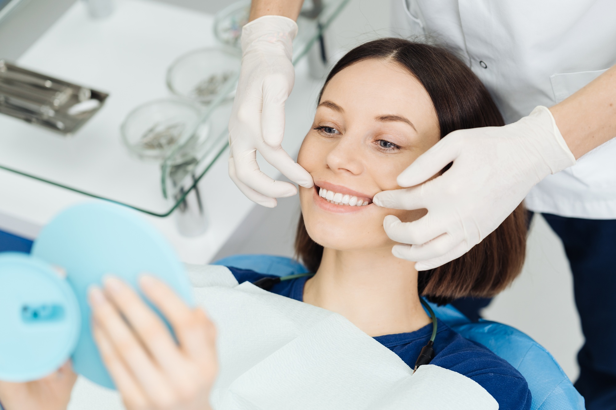 Dentist hands and happy patient looking in mirror after treatment